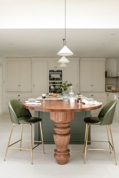 a kitchen with an island table and green chairs