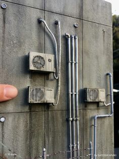 a hand pointing at some electrical equipment on a wall