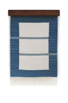 a blue and white rug hanging from a wooden hanger on a wall with a wood frame