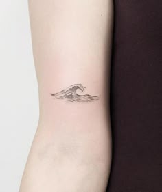 a woman's arm with a small wave tattoo on the back of her left arm