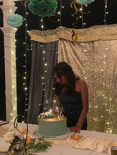 a woman standing in front of a table with a cake on it and lit candles