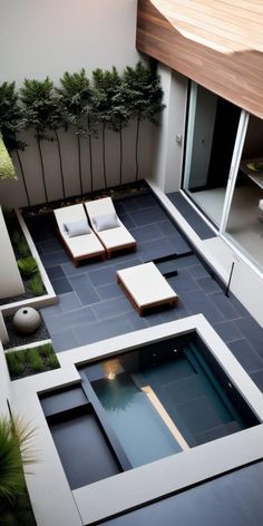 an outdoor living area with lounge chairs and plants on the side of the building,