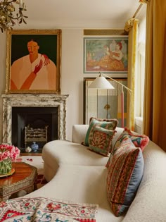 a living room filled with furniture next to a fire place and paintings on the wall