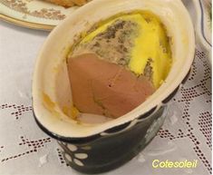 an egg in a bowl on a table next to some croissants and bread