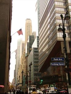 the city street is lined with tall buildings and traffic lights, as well as an american flag