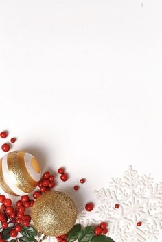 christmas decorations on white background with red berries and gold bauble ornament