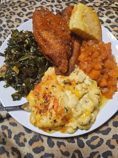 a white plate topped with meat, pasta and veggies on top of a leopard print table cloth