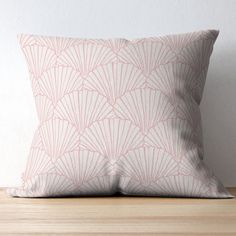 a pink and white pillow sitting on top of a wooden table next to a wall