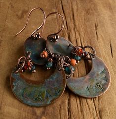 Primitive copper stamped two part connected earring design with crescent shaped lower and oval shaped upper components. The solid copper components are treated with a green patina and a coat of jewelry grade lacquer to protect the color. Dangles in sun drenched orange and watery blue add a touch of color. The solid copper earwires are a four ball cluster design, making the total length of the earrings 2.5 inches, and still a comfortable weight for their size. Your package will come to you gift w Bohemian Stamped Copper Jewelry, Primitive Jewelry, Patina Earrings, Rustic Orange, Metal Stamped Jewelry, Cluster Design, Paper Bead Jewelry, Green Patina, Beaded Jewelry Designs