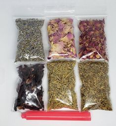 four bags filled with different types of flowers and herbs next to a red plastic marker