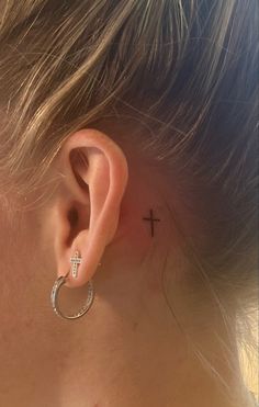 a woman with a small cross behind her ear