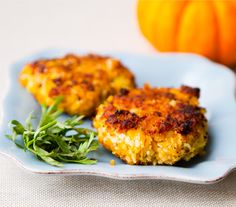 two crab cakes on a blue plate next to a pumpkin