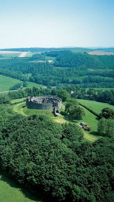 an aerial view of a castle in the middle of a green field surrounded by trees