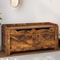 an old wooden trunk is sitting on the floor in front of a wall with a hat hanging above it