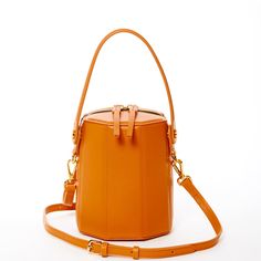 The cute Harper unexpected geometric shape gives this orange leather crossbody bag a playful but sophisticated runway savvy look. With its gold hardware, its small handle allows this orange leather bucket bag to swivel and be held in hand as a bucket. Its top zipper will keep your contents secure inside, while the cotton lined interior with 3 compartments keeps everything organized. This trendy designer crossover barrel bucket purse comes with a long and comfortable leather strap that can be flu Convertible Backpack Purse, African Accessories, Bucket Purse, Bucket Handbags, Mini Bucket Bags, Mini Bucket, Bag Dark, Dark Orange, Leather Bucket Bag