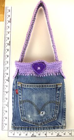 a purse made out of jeans with a purple button on the front and side pocket