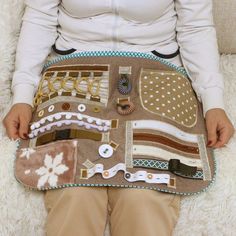 a woman is sitting on the floor holding a purse made out of fabric and buttons