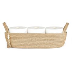 three rolls of toilet paper sitting in a woven basket with two white candles on top