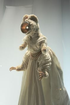 a teddy bear dressed in a dress and with a lamp on its head is standing up