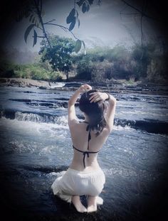 a woman sitting in the water with her hands on her head