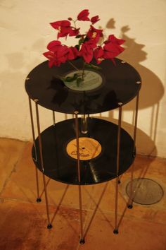 two black tables with flowers on them in front of a wall