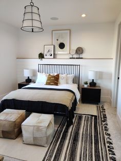 a bedroom with a bed, ottomans and pictures on the wall