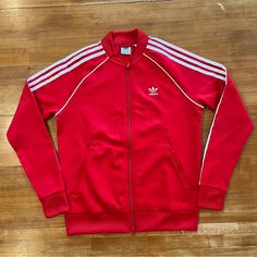 Classic Adidas Jacket In Red With White Stripes. Heavyweight Poly/Cotton Blend, Regular Fit, And Very Comfortable. Full Zipper Jacket Has A Red Hem, Cuffs, And Collar, Front Zip Pockets, Adidas Trefoil Logo On Left Chest, And The Classic Three Stripes Down Each Arm With Additional Striping From Front To Back. Nwt Mint Condition. Red Adidas Jacket Outfit, Track Fits, Red Adidas Jacket, Adidas Zip Up Hoodie, Jeremy Scott Adidas, Adidas Zip Up, Adidas Vintage, Red Jumper, Green Leather Jackets