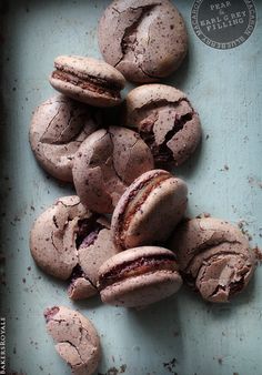 chocolate macaroons are sitting on a blue surface with their fillings spilled over them