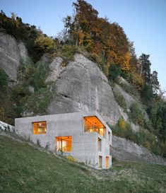 a house built into the side of a mountain with windows lit up at night time