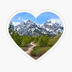 a heart shaped sticker with mountains and trees in the background on a sunny day