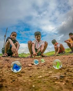 four boys are playing with soap bubbles on the ground