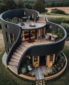 a circular house with stairs and plants on the roof, surrounded by grass in front of it