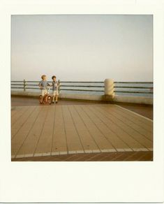 two children are standing on the edge of a pier looking at something in the distance