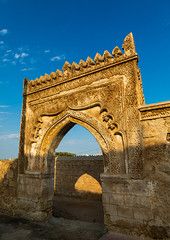 an old building with a stone arch in the middle and blue sky behind it on a sunny day