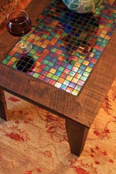 a coffee table with a glass of wine on top of it next to a vase