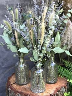 three vases filled with flowers sitting on top of a tree stump