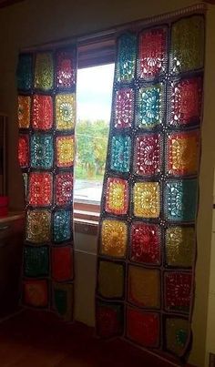 the window is decorated with multicolored crocheted squares and has a wooden floor