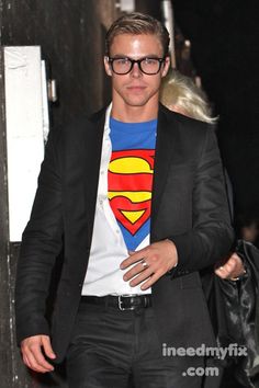 a man wearing a superman t - shirt and black suit with a white tee underneath