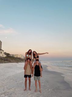 three people are standing on the beach with their arms around each other