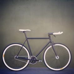 a black bike with white spokes against a green wall