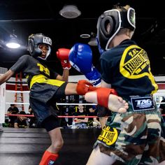 two young boys are practicing boxing in the ring with their gloves on and one boy is wearing