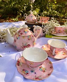 pink tea set sitting on top of a white table cloth