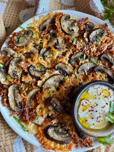 a white plate topped with pizza covered in mushrooms next to a bowl of ranch dressing