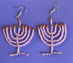 a pair of pink beaded menorah earrings on a purple background with orange beads