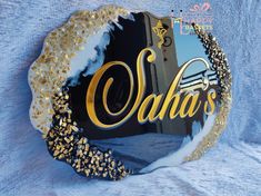 a glass ornament with the name saha's on it in gold and black