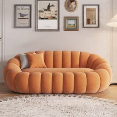 a living room with an orange couch and pictures on the wall above it, along with a rug