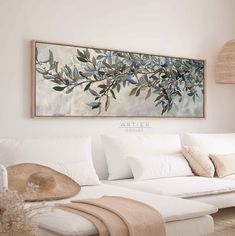 a living room with white couches and paintings on the wall above it's headboard