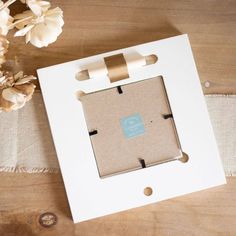 a white box with a brown ribbon around it and some flowers on the table next to it