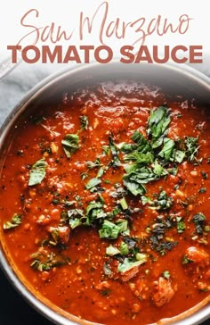 a large pot filled with tomato sauce and garnished with fresh basil on top