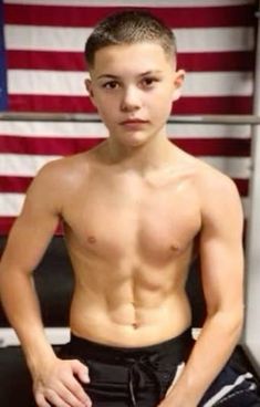 a young man standing in front of an american flag with his hands on his hips